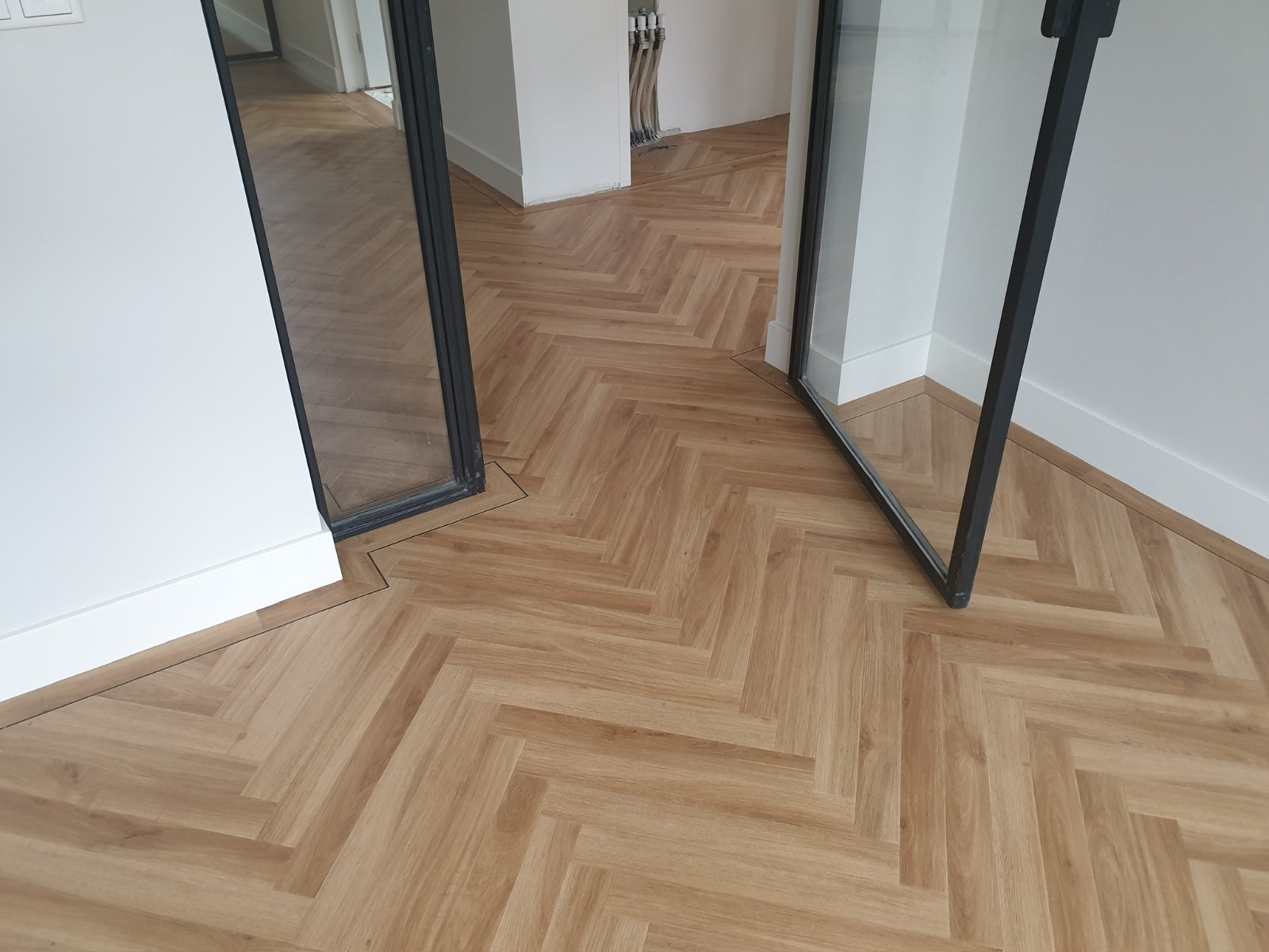 Detail van een visgraatvloer bij een stalen pui