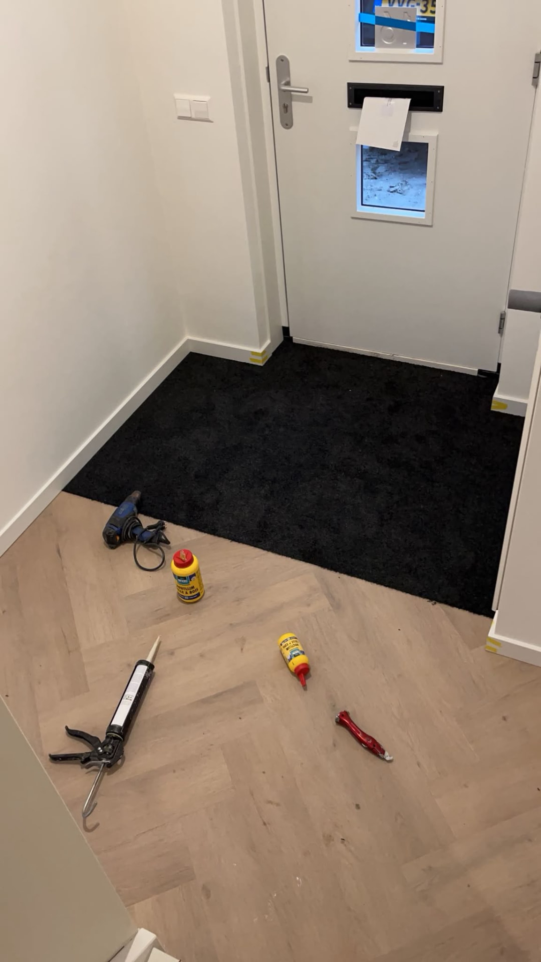 Donkere mat in een hal naast een lichte visgraatvloer